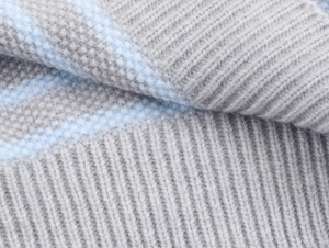 Dettaglio del tessuto a maglia a righe grigio e celeste con trama a coste morbide