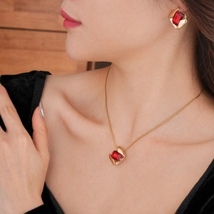 Detail of elegant gold necklace and earrings set with large red rectangle gemstones