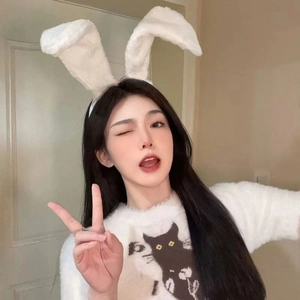 Detail of white plush bunny ears headband worn by a smiling model in a cat sweater