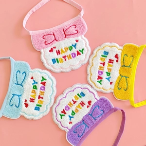 Detail of four colorful pet birthday bibs with happy birthday embroidery and lace trim