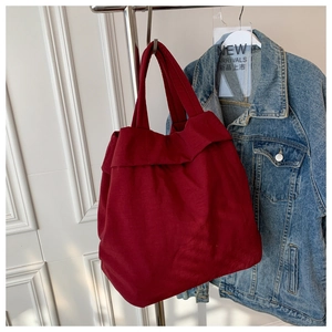 Burgundy nylon canvas tote bag hung next to a denim jacket in a lifestyle setting