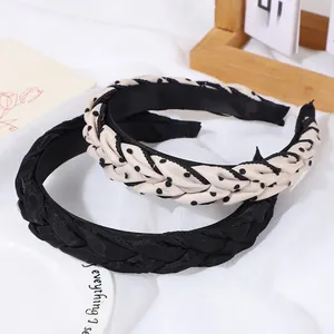 Détail de serre-têtes tressés à pois et noirs sur un fond de tissu blanc minimaliste