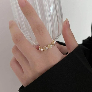 Detailed close-up of a French style leaf ring with pearls and zircons on a hand