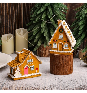 Detailed view of gingerbread resin houses with LED lights and snow-covered roofs on wood