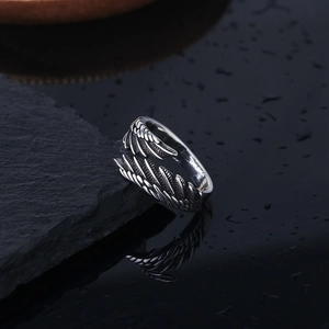 Macro shot of retro angel wing ring with detailed silver feathers on dark stone base