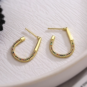 Close-up of U-shaped gold earrings with colorful rainbow cubic zirconia inlay on white tray