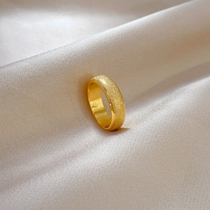 Close-up of golden matte titanium ring on elegant white silk fabric background