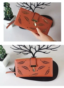 Detailed close-up of long wallet featuring laser-cut leaf pattern and metal pendant