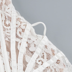 Close-up of white lace fabric with floral patterns and satin trim on a bustier dress