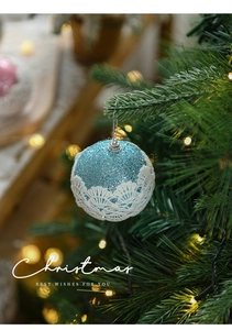 Detailed close-up of an 8cm blue glitter Christmas ball with white lace trim and silver string