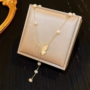 Detailed view of golden butterfly pendant necklace with pearls and diamonds in a gift box