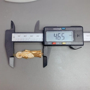 Digital caliper measuring the 46.5mm gold Saint Jude religious pendant with zircon