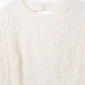Mini abito in pizzo bianco crema con chiusura a bottone sul retro e dettagli traforati