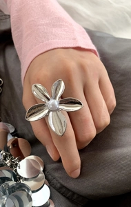 Detail of silver hollow flower ring with a center white pearl on a female finger