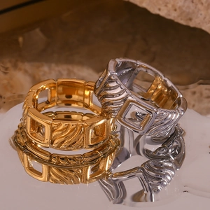 Macro view of gold and silver hollow chain textured square rings on a stone surface