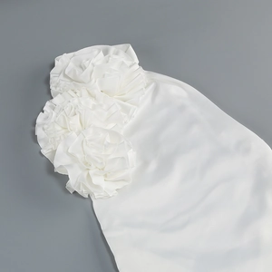 Détail de trois grandes fleurs 3D artisanales sur une robe licou blanche en satin