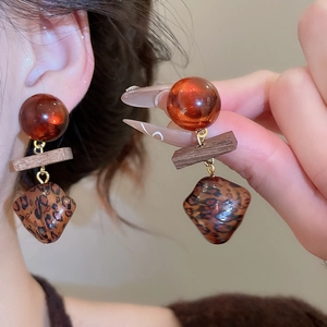 Gros plan sur des boucles d'oreilles rétro en bois et léopard avec perles en ambre