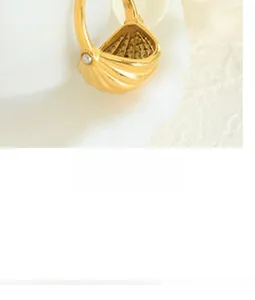 Macro detail of 18K gold-plated shell ring with vertical texture and center pearl inlay