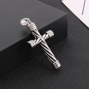 Close-up of silver stainless steel cross pendant with twist pattern on black texture box