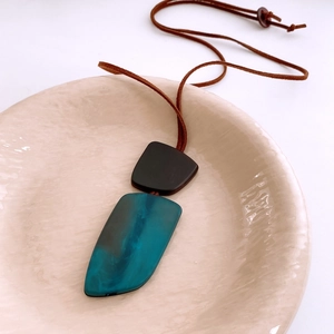 Macro detail of irregular horn pendant necklace with blue marble texture on ceramic plate