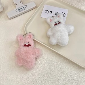 Close-up of cute plush bear charms with metal bead chains on a beige tray with card