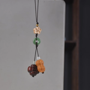 Detailed view of handmade wood carved persimmon and peanut keychain with jade ring accents