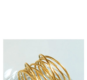 Detailed view of gold plated multi-layer spiral ring placed on glass edge
