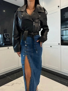 Détail d'une jupe en jean taille haute à boutons, fente et veste de motard en cuir noir