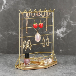 Detail of multi-tier gold metal jewelry display stand with light wood base and geometric frame
