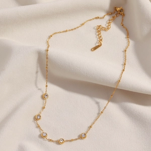 Détail du collier à billes plaqué or 18 carats avec zircons ronds sur tissu blanc doux