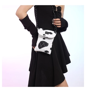 Detail of white quilted cow-print fabric crossbody bag with braided rope shoulder strap