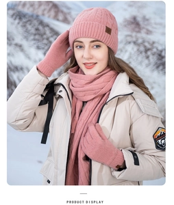 Pink knitted winter set with pompom hat, scarf and gloves shown in a snowy landscape