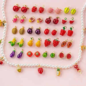 Macro shot of colorful fruit and vegetable enamel charms and pearl necklace DIY material
