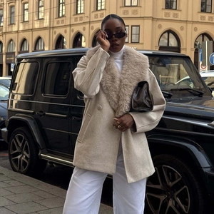 Eleganter beiger mittellanger Mantel mit Pelzkragen, Handtasche mit Muster und weißer Hose für Damen