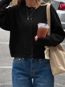 Close-up of black buttoned cardigan with soft knit fabric on a model in street style