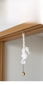 Nautical seahorse wind chime with rustic white finish and metal bell on a door frame