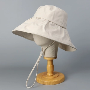 Detail of beige wide brim sun hat featuring adjustable chin strap for outdoor UV protection