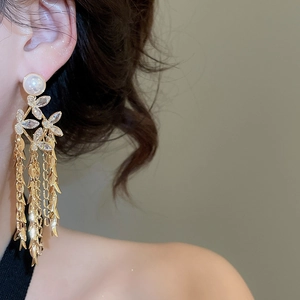 Detailed close-up of 18K gold plated flower pearl earrings with long leaf fringe tassels