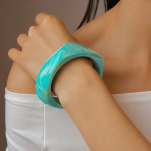 Macro detail of a wide blue resin bangle with marble texture on a female wrist