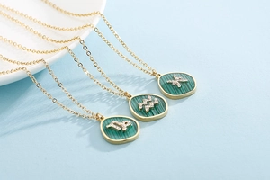 Macro view of gold necklaces with malachite pendants featuring zodiac signs