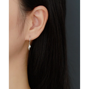 Detail of silver S925 shell drop earring worn on model featuring a minimalist hoop design