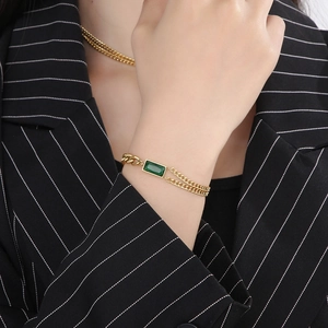 Detailed shot of a gold cuban link bracelet featuring a rectangular emerald gemstone