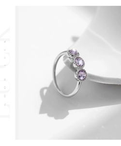 Macro shot of silver ring featuring three round purple zirconias on a minimal ceramic stand