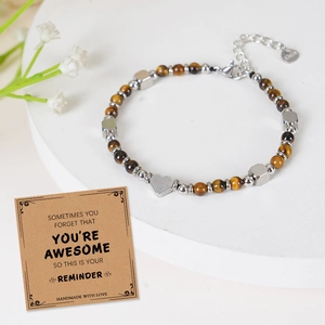 Detail of tiger eye bead bracelet with silver heart charm and motivational card