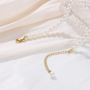 Detail of white pearl necklace with gold lobster clasp and adjustable metal chain