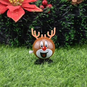 Wind-up Christmas reindeer toy walking on grass with festive pine and flower background