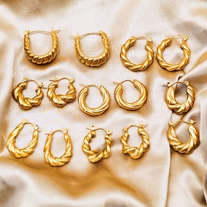 Detail of 18K gold plated stainless steel twisted hoop earrings on silk background