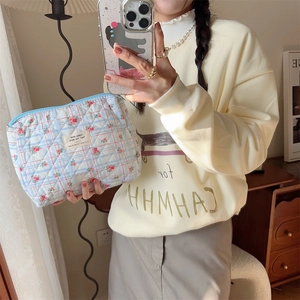 Detailed shot of quilted floral and checkered cosmetic bag with a light blue zipper closure