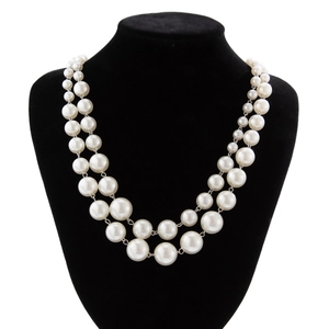 Detail of double-layer faux pearl necklace on black velvet mannequin with elegant finish