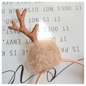 Detail of rose gold glitter antlers and soft beige plush balls on a festive Christmas headband